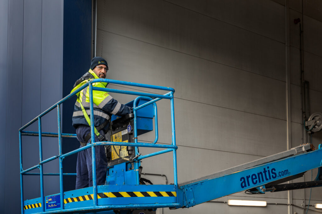 Foto van een medewerker op een hoogwerker